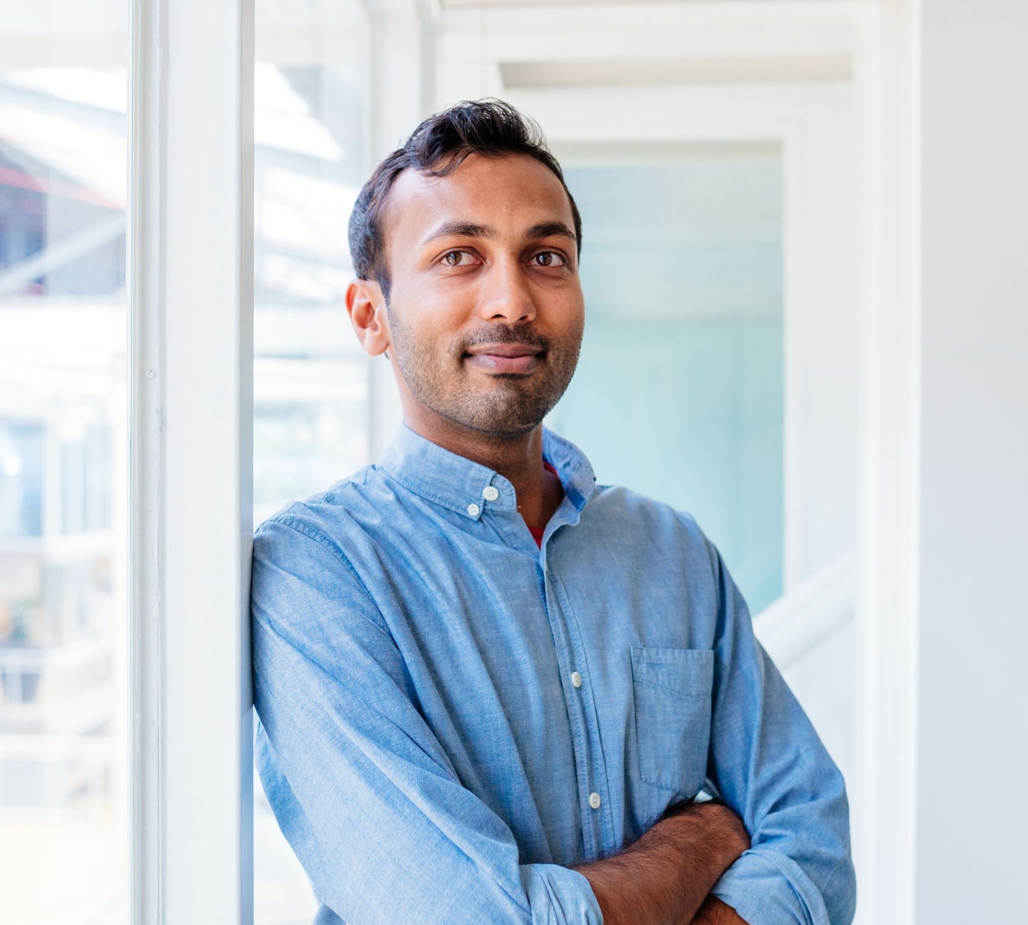 Man standing in front of window with arms crossed